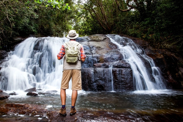 Wanderer steht vor einem Wasserfall im Dschungel, Sri Lanka