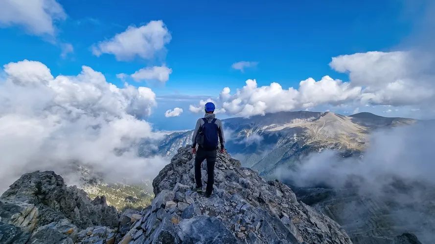 Rückansicht eines Mannes auf dem wolkenbedeckten Berggipfel des Mytikas Olymp