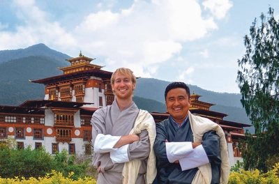 Trekker im traditionellen Go vor dem Punakha Dzong - Frederik Schwall